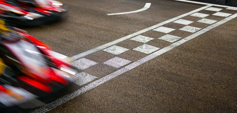 Barn i hjälm kör gokart på landsväg vid skylt.